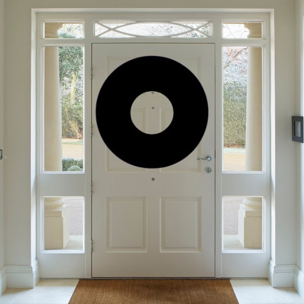 Oceanside COE 96 Glass Precut Silhouette of a Christmas wreath shape displayed on a white front door with side windows, viewed from inside a home.