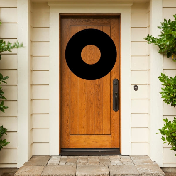 Bullseye COE 90 Glass Precut Silhouette of a Christmas wreath shape placed on a wooden front door, framed by white siding and green bushes.