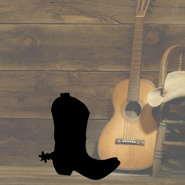 Bullseye COE 90 Glass Silhouette of a cowboy boot with a spur, placed in front of a rustic wooden wall alongside a classical guitar, a straw cowboy hat, and a wooden chair.